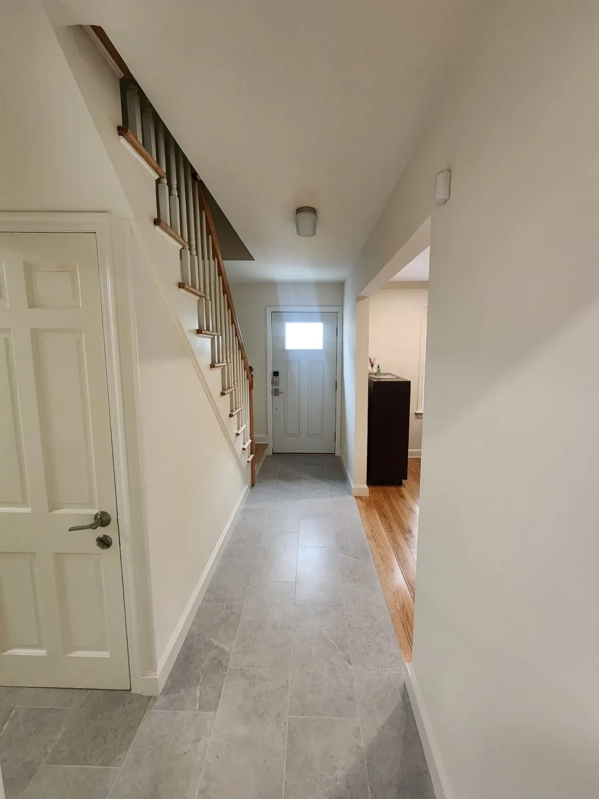 Entry hall with new large-format floor tile beside original hardwood in a Scarsdale, NY home
