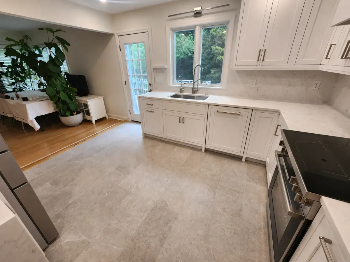 Undermount sink beneath a window with stone countertops and a door to the deck in a Scarsdale kitchen renovation